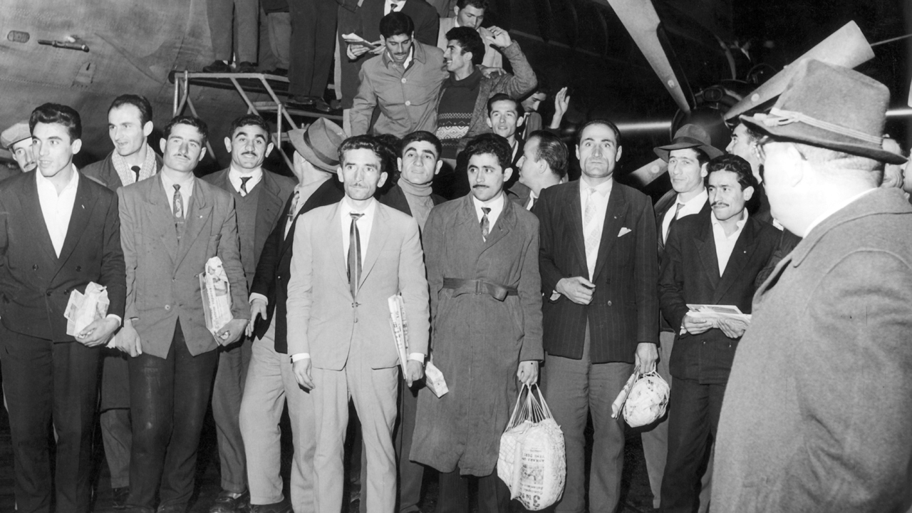 Türkische Gastarbeiter nach Ankunft vor einem Flugzeug