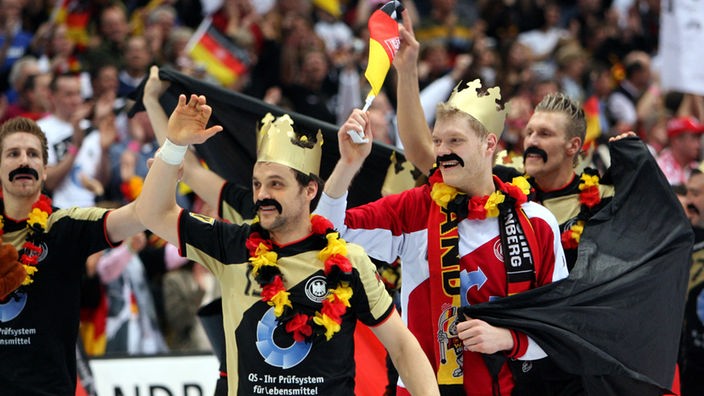 Deutsche Spieler mit Pappkronen und angeklebten Schnauzbärten bejubeln WM-Sieg