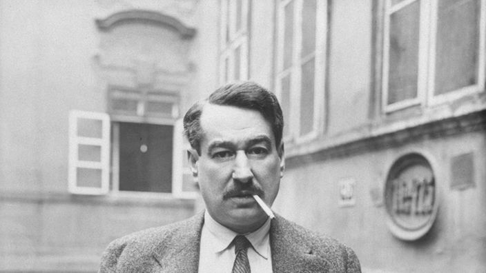 Egon Erwin Kisch vor Haus mit Zigarette im Mund (1932 s/w)
