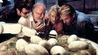 Im Film "Jurassic Park" betrachten Dr. Ian Malcom (Jeff Goldblum, l.), John Hammond (Richard Attenborough), Dr. Ellie Sattler (Laura Dern) und Dr. Alan Grant (Sam Neill) die Geburt eines Dinosauriers
