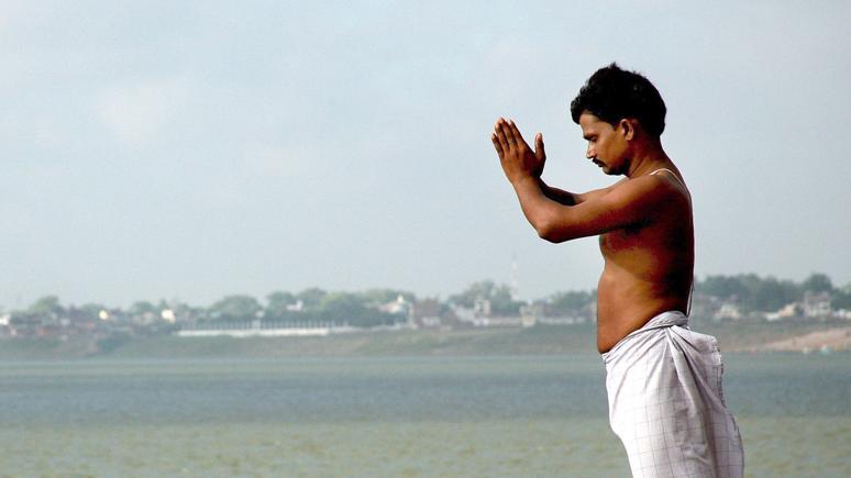 An Mann steht am Ganges und betet