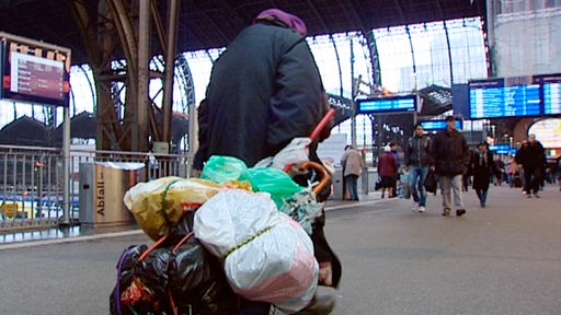 Obdachloser zieht sein Gepäck am Bahnhof hinter sich her