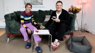 Bettina Böttinger auf einer Couch mit Guido Maria Kretschmer. Beide schauen in die Kamera