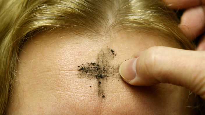 Ein Aschenkreuz bekommt eine Katholikin auf die Stirn gemalt. 