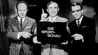 Die Moderatoren Dieter Adler, Ernst Huberty und Addi Furler mit einem Sportschau-Schild 1967.