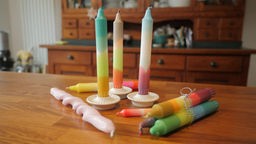 Das Bild zeigt mehrere gefärbte Kerzen auf einem Tisch.  