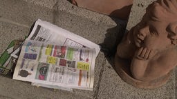 Das Bild zeigt eine Zeitung auf dem Boden.