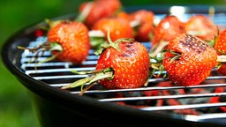 Erdbeeren auf Spießen brutzeln auf einem Grill.
