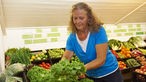Barbara Büsch mit Salatkopf in der Hand, im Hintergrund jede Menge Gemüse aus ihrem Hoflieferdienst