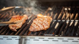 Das Bild zeigt zwei Stück STeak auf einem Gasgrill.