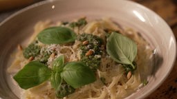 Das Bild zeigt Nudeln mit Pesto, serviert auf einem tiefen Teller. 