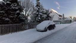 Ein geparktes Auto ist mit Schnee bedeckt.
