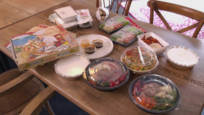 Auf einem Tisch stehen etliche To-Go-Verpackungen mit verschiedenen Gerichten.