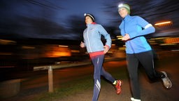 Das Bild zeigt zwei Joggerinnen, die im dunkeln joggen. 