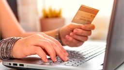 Das Bild zeigt eine Person beim Online-Shopping am Laptop.
