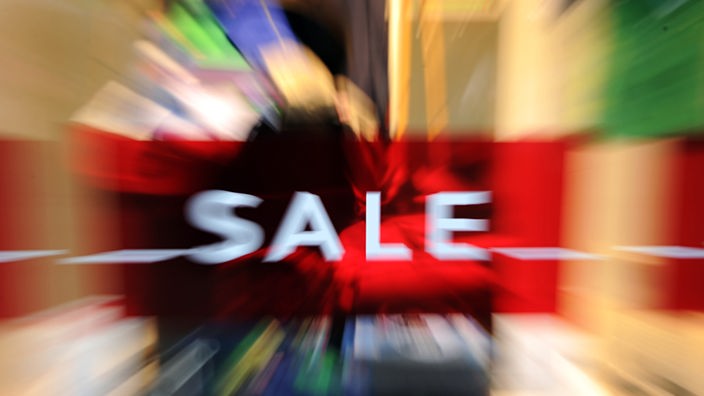 Verschwommene Szene beim Einkaufen mit "Sale"-Schild