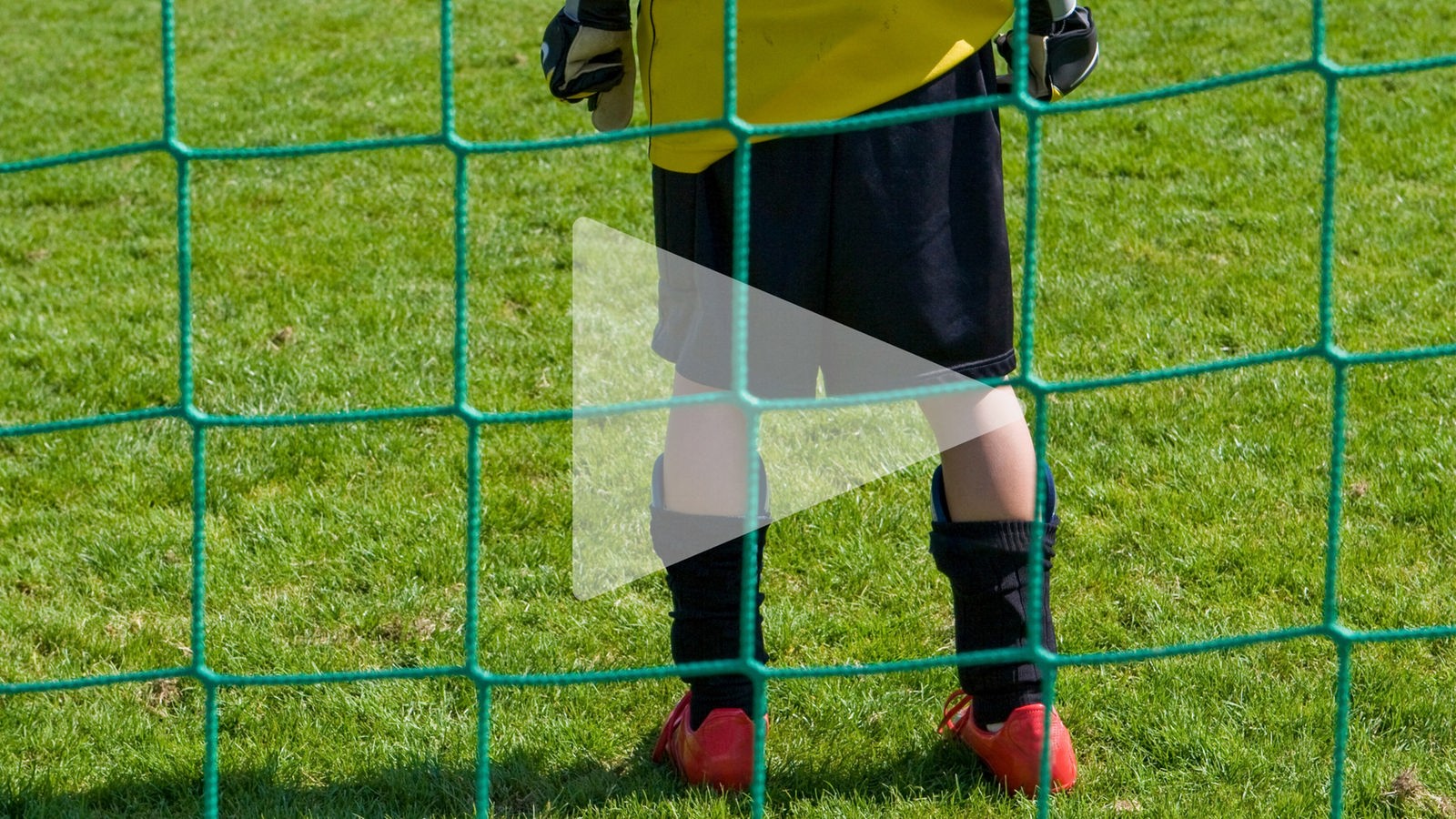 Das Bild zeigt ein Kind in einem Fußballtor.