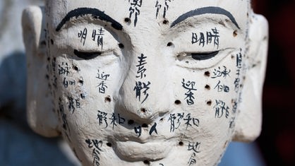 Kopf einer Buddha-Figur mir chinesischen Schriftzeichen, Akupunktur-Kopf