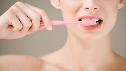 Das Bild zeigt eine Frau, die sich die Zähne putzt.