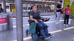 Ein Mann im Rollstuhl an einem Bahngleis