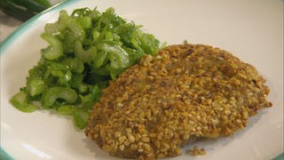 Lammschnitzel mit Haselnussknusper und Selleriesalat auf einem Teller angerichtet