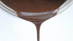 Geschmolzene Schokolade wird aus einem Topf gegossen