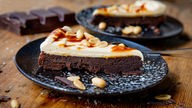 Das Bild zeigt selbstgemachten Brownie mit Erdnussbutter-Creme und Karamell auf einem Teller.