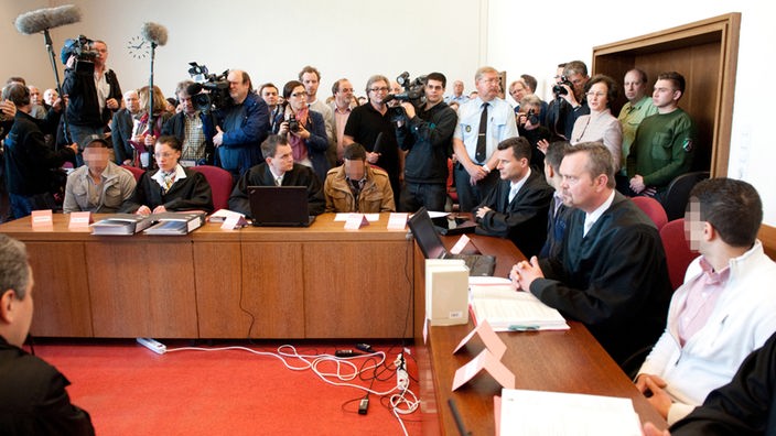 Die Angeklagten sitzen mit ihren Anwälten auf der Anklagebank im Landgericht Detmold.