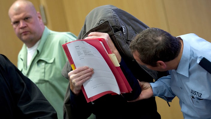 Der Angeklagte Ahmed S. hält sich am 06.03.2013 im Landgericht in Düsseldorf auf der Anklagebank eine Mappe vor das Gesicht