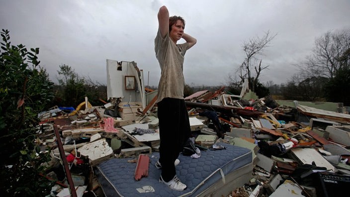 Nach dem Tornado - Junger Mann in den Trümmern seines Zuhauses