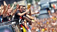 Die Spieler der Fussball-Nationalmannschaft jubeln beim ihrem Empfang in Berlin von einem Lkw