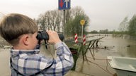 Mit einem Fernglas blickt der 6-Jährige Patrik an der Hochwassergrenze bei Grietherort am Niederrhein auf den Alt-Rheinarm hinaus, 1998