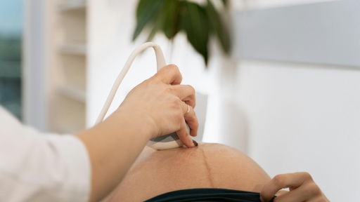 Ultraschallgerät wird an einen schwangeren Bauch gehalten