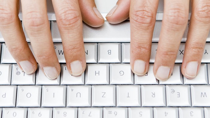 Schreibende Hände auf einer Laptoptastatur