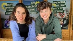 Anna di Bari und Timo Eismann im Grünenstand in der Bochumer Innenstadt, im Hintergrund Wahlplakate