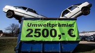 Zwei Schrottfahrzeuge liegen als Werbung für die Umweltprämie in einem Container