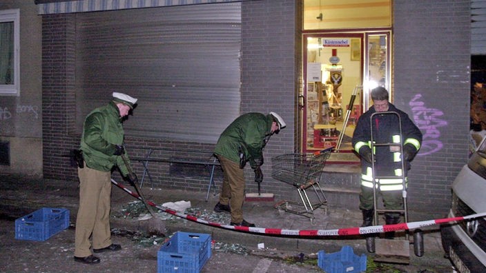 Polizeibeamte kehren nach einen Bombenanschlag am 19.01.2001 auf ein Lebensmittelgeschäft in Kölner Probsteigasse Scherben zusammen