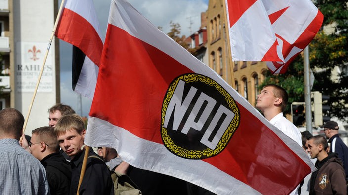 Mitglieder der rechtsextremen NPD tragen bei einer Demonstration Fahnen mit dem Logo der Partei