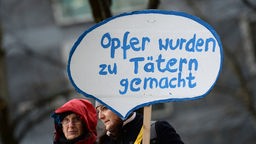 Mitglieder der Initiative «Keupstraße ist überall» stehen vor dem Oberlandesgericht in München und halten ein Schild mit der Aufschrift «Opfer wurden zu Tätern gemacht» in die Höhe