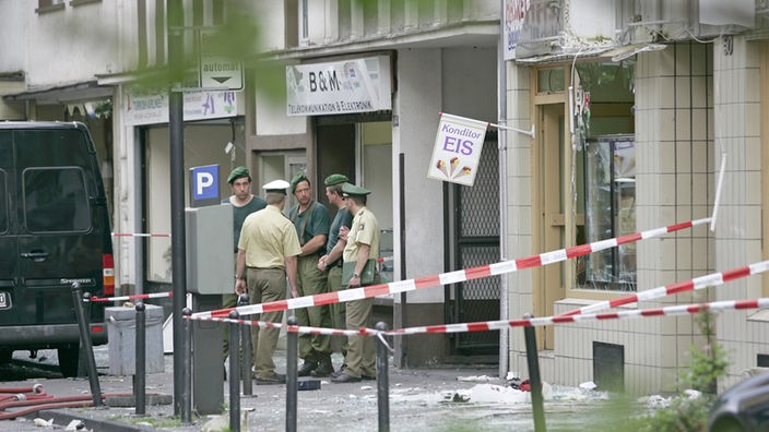 Polizisten untersuchen am 09.06.2004 in Köln-Mülheim die Trümmer einer Bombenexplosion