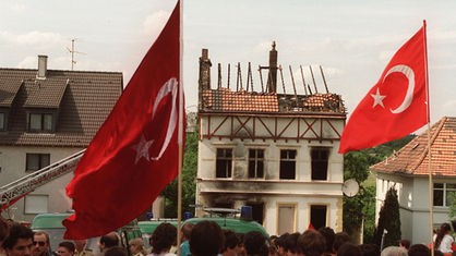Demonstranten tragen am 29. Mai 1993 vor dem ausgebrannten Haus der Familie Genc in Solingen türkische Fahnen.