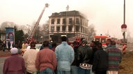Dichtgedrängt stehen Asylbewerber  am 19. Januar 1996 vor dem ausgebrannten Haus