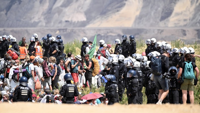 Aktivisten vom Aktionsbündnis "Ende Gelände" stehen umringt von der Polizei am Rand des Tagebaus