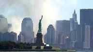Freiheitsstatue hebt sich vor der Rauchwolke des eingetürzten World Trade Centers ab