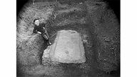 Ein Junge lehnt bei einer Ausgrabung am Erdreich