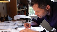 Illustrator Jörg Mailliet an seinem Schreibtisch in Rennes
