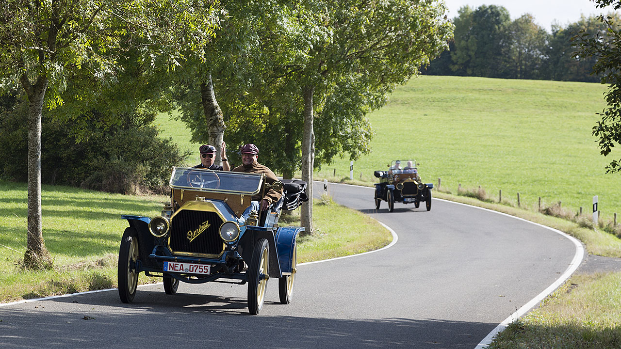 Zwei Overland-Oldtimer fahren auf einer Landstraße in der Eifel