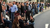 Reisende warten  in Düsseldorf vor einem Parkhaus am Flughafen Düsseldorf