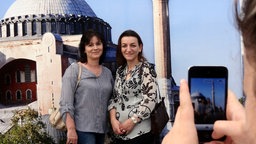 Zwei Frauen lassen sich vor einer Fotowand fotografieren, die die Istanbuler Hagia Sophia zeigt.