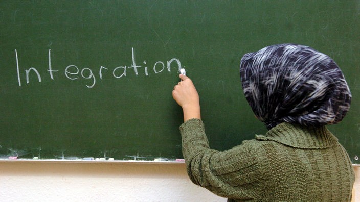 Eine türkische Frau schreibt im Schulungsraum an der Tafel